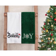 two towels on a ladder next to a christmas tree