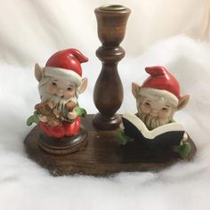 two gnome figurines sitting next to a candle