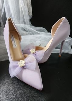 a pair of wedding shoes with a bow on the heel and pearls at the toe