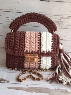 a brown and white handbag sitting on top of a wooden table next to a chain