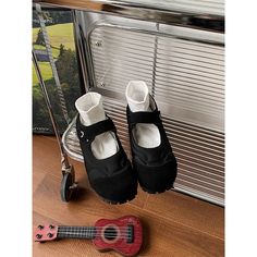 a pair of black shoes sitting on top of a wooden floor next to a ukulele