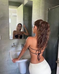 a woman standing in front of a bathroom mirror