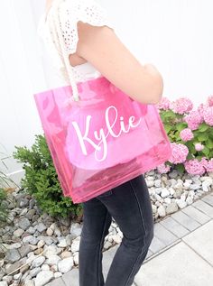 a woman carrying a pink shopping bag with the word kylie on it's side