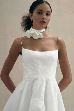 a woman in a white dress with a flower on her neck