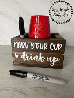 a cup and pen sitting on top of a wooden box that says, make your cup go drink up