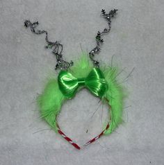 a green headband with red and white candy canes attached to it, sitting on top of snow covered ground