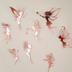 several tinkered fairy figurines are arranged on a white surface, including one pink and one red