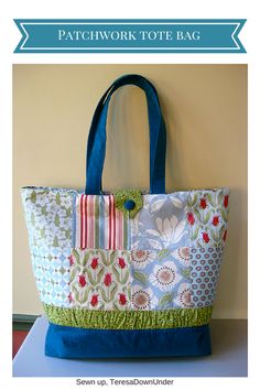 a blue and green tote bag sitting on top of a table next to a wall