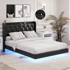 a bed with white sheets and black headboard in a room next to a potted plant