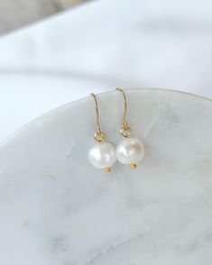 A pair of elegant pearl earrings are so pretty and you can wear them all day or night and match them with all your outfits. They make a perfect gift for your mother or girlfriend, a birthday gift for every woman and of course it's a nice and affordable gift idea. Details: -The pearls measure approximately 1cm -The ear wires measure approximately 1.6cm from the top of the hook to the bottom were the pearl attaches. -Overall measurement from top of ear hook to bottom of pearl approximately 1.8cm. Elegant Round Earrings For Mother's Day, Elegant Mother's Day Pearl Earrings For Pierced Ears, Elegant White Earrings For Mother's Day, Elegant Round Mother's Day Earrings, Elegant Hypoallergenic Earrings For Mother's Day, Minimalist Pearl Earrings As Gift, Minimalist Pearl Matching Earrings As Gift, Dainty Pearl Earrings With Ear Wire For Gift, Minimalist Matching Pearl Earrings Gift