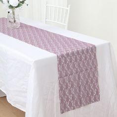 the table is covered with a pink and white table runner that has an intricate design on it