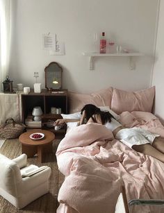 a woman laying on top of a bed in a bedroom next to a table and chair