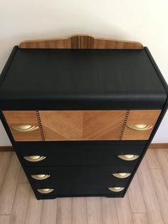 a black and wood cabinet with brass handles