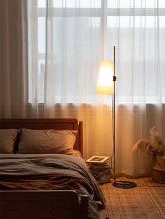 a bedroom scene with focus on the floor lamp and bed in the foreground,