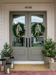 two christmas wreaths on the front door of a house