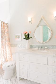 a bathroom with a sink, toilet and flower vase on top of the vanity area