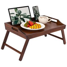 a wooden tray with a plate of fruit on it and a laptop computer next to it