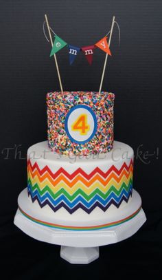 the cake is decorated with colorful icing and has a number one on it's top