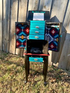 a chair made out of old mailboxes sitting in the grass next to a fence