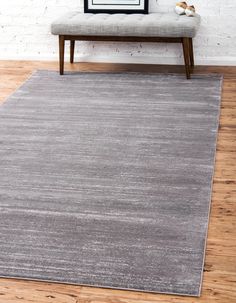 a gray rug in front of a white brick wall with a bench on the side