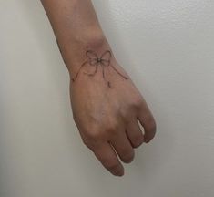 a woman's hand with a bow tattoo on her left wrist and the other arm