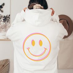 Spread some good vibes in your over-sized hoodie with a giant double vision smiley face printed on the back. Exclusively designed by Parcel 23. Direct to garment printed in the USA (this is not a transfer, it's the real deal). Select your size and favorite color option, and we'll have it produced and delivered in about a week. Gildan Unisex Heavyweight Blend Hoodie. Classic fit, Unisex sizing.  Size up for a relaxed look. Size down if you prefer a sporty, fitted look. 50% cotton, 50% polyester Soft and warm. Madde to last a lifetime. Any questions or custom requests, give a shout via Etsy Messages. We're happy to help! BIG THANKS for your consideration to shop small. parcel23.etsy.com White Fun Winter Hoodie, Fun White Winter Hoodie, Fun White Hoodie For Fall, Fun Hoodie Sweatshirt With Drawstring Hood, Fun Sweatshirt With Drawstring Hood, Fun Hooded Graphic Print Sweatshirt, Fun Graphic Print Hoodie For Streetwear, Fun Graphic Print Hoodie Sweatshirt, Fun Graphic Print Hoodie