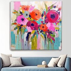 an abstract painting with pink and red flowers on a blue couch in front of a white wall