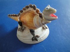 a sea shell with an animal figure on it's back sitting on a blue surface