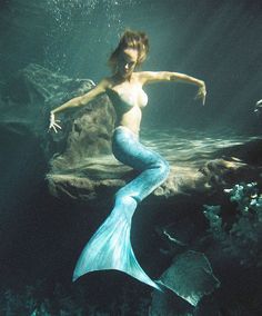 a woman in a blue dress standing under water