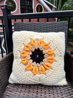 a crocheted pillow sitting on top of a wicker chair