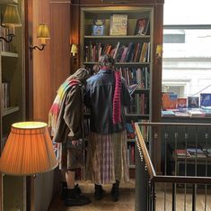 two people standing in front of a bookshelf with lots of books on it