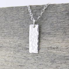 A dainty classic small silver bar necklace. This necklace is specifically created to be just a whisper along your neck line, dainty, delicate, lightweight and beautiful. Perfect for layering with your favorite pieces.Petite and dainty, this necklace consists of a 5/8 inch Sterling Silver rectangle bar, hammered with my Classic texture and suspended from dainty 1.9mm Sterling Silver cable chain. The pendant is suspended just over 5/8 inch in length from the chain and tumble polished for shine.  P Elegant Silver Rectangular Bar Necklace, Silver Dainty Bar Necklace For Everyday, Silver Sterling Silver Bar Necklace With Rectangular Pendant, Silver Bar Necklace With Delicate Chain For Everyday, Silver Minimalist Necklace With Rectangular Pendant, Dainty Sterling Silver Bar Necklace For Everyday, Simple Silver Necklace With Rectangular Pendant, Everyday Silver Bar Necklace With Delicate Chain, Minimalist Silver Bar Necklace As Gift