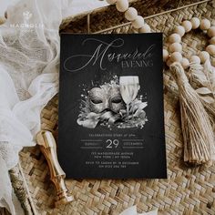 a black and white masquerade evening party card on a wicker mat with tassels