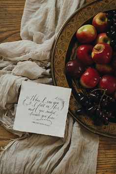 a bowl filled with fruit on top of a table next to a napkin and cloth