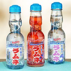 three bottles of soda sitting next to each other on a blue tablecloth covered surface