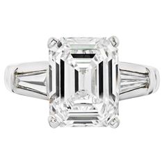 Stunning ring when you want to show up! Mounted with an impressive 4 carat Emerald Cut Diamond that is mounted in platinum accented by baguette cuts. The Center diamond is a certified K/VS2 GIA stone. Three-stone diamond engagement rings have always been a classic. Especially in platinum! We noticed that this center diamond looks bigger than a typical 4 carat and the savings you are getting shopping in K color category are just unbelievable. Beautiful ring that delivers a lot of wow factor! Beli White Gold Octagon Diamond Ring With Baguettes, White Gold Octagon Diamond Ring With Baguette Diamonds, Octagon White Gold Diamond Ring With Baguette Diamonds, Luxury Octagon Diamond Ring With Baguette Diamonds, Luxury Octagon Baguette Diamond Ring, Formal Octagon Baguette Diamond Ring, Platinum Diamond Ring With Baguette Emerald Cut, Classic Octagon Diamond Ring With Baguette Diamonds, Gia Certified Classic Rectangular Diamond Ring