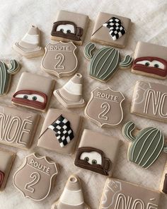 decorated cookies are arranged in the shape of cars and road signs on a white tablecloth