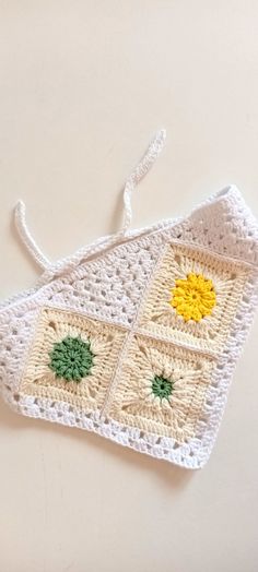 a crocheted dishcloth with yellow and green flowers on the front, sitting on a white surface