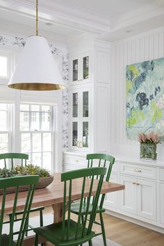 a dining room table with green chairs and a painting on the wall