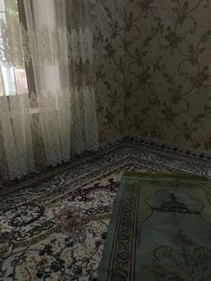 a rug is laying on the floor in front of a window with sheers and curtains