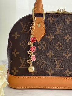 a brown and tan louis vuitton handbag with flowers on the handle is sitting next to a white flower