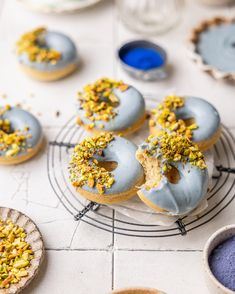 blue frosted doughnuts with sprinkles on a cooling rack next to other pastries