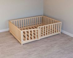 a wooden crib sitting on top of a hard wood floor next to a wall