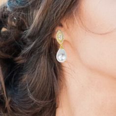 a close up of a woman's ear wearing gold and white earrings with diamonds