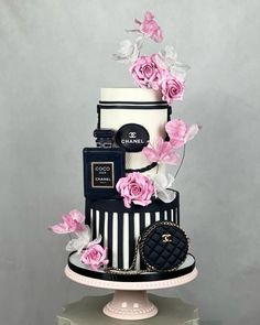 a three tiered black and white cake with pink flowers on top is adorned with chanel purses