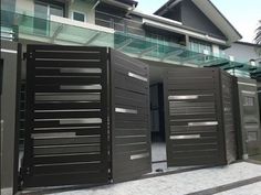 two large black gates are open in front of a house with glass balconies