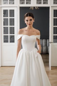 a woman in a white wedding dress posing for the camera with her hands on her hips