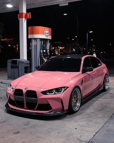 a pink car parked in front of a gas station