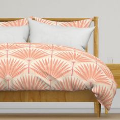 an orange and white bed with two pillows on top of it next to a wooden headboard