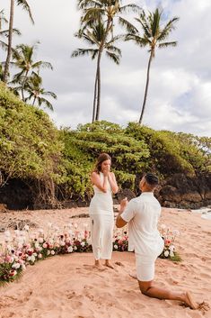 a man kneeling down next to a woman on a beach